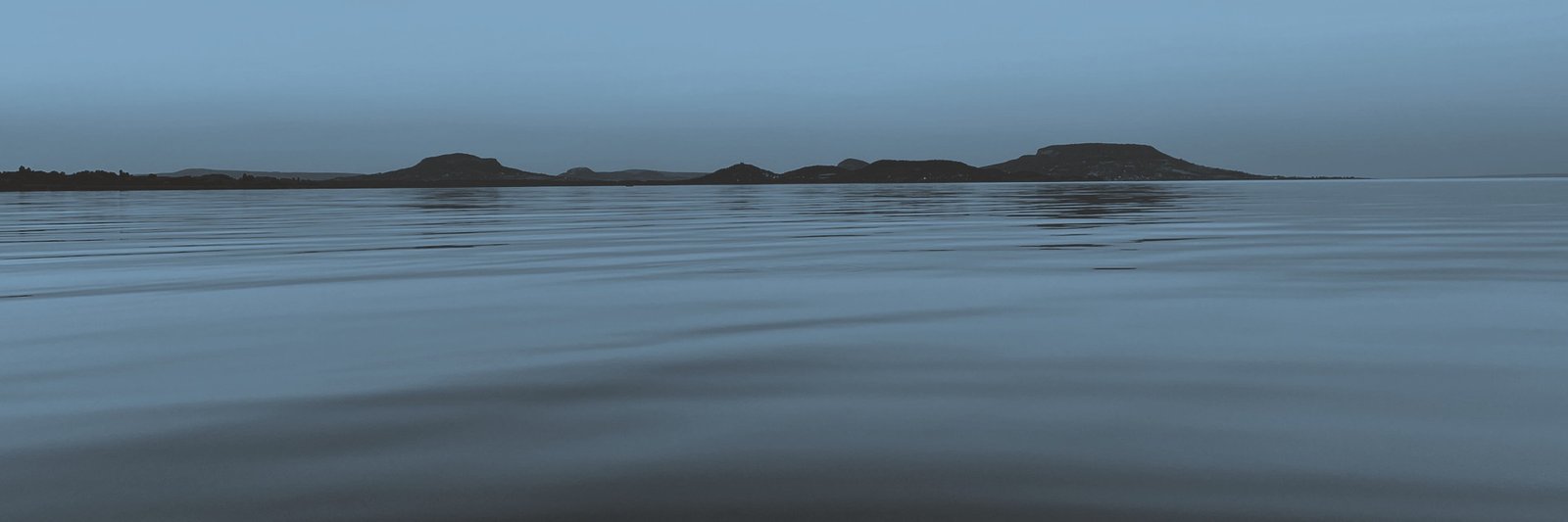 The ten volcanic hills of the Balaton Uplands seen across the lake from Balatongyörök at dusk